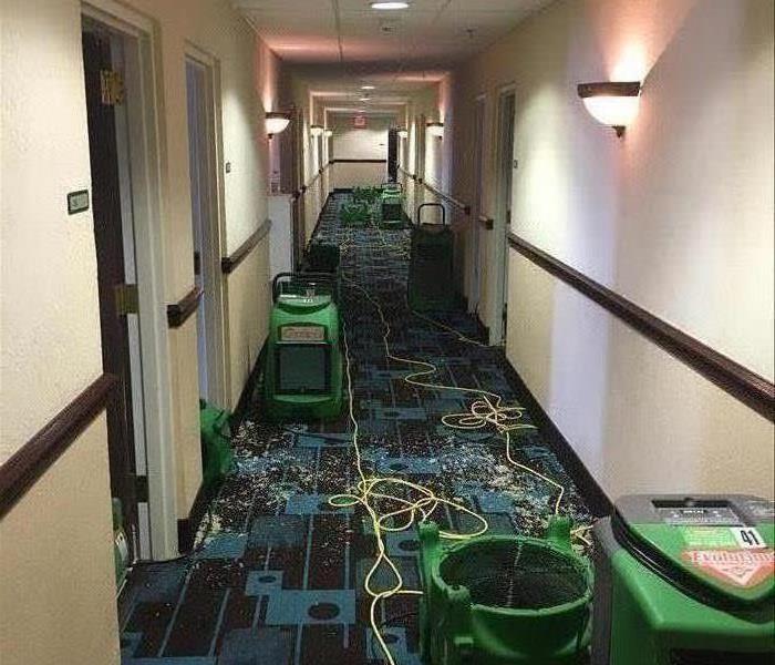 hotel hallway with dehumidiifers and other equipment removing water