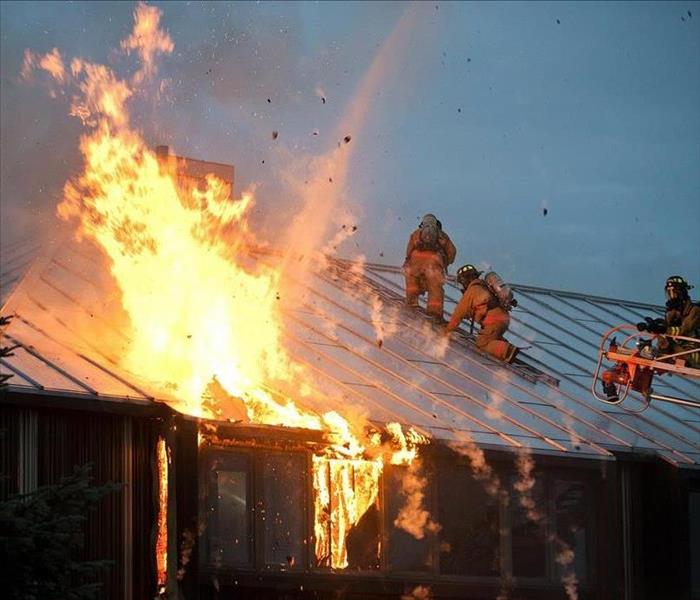 house on fire with fireman fighting fire